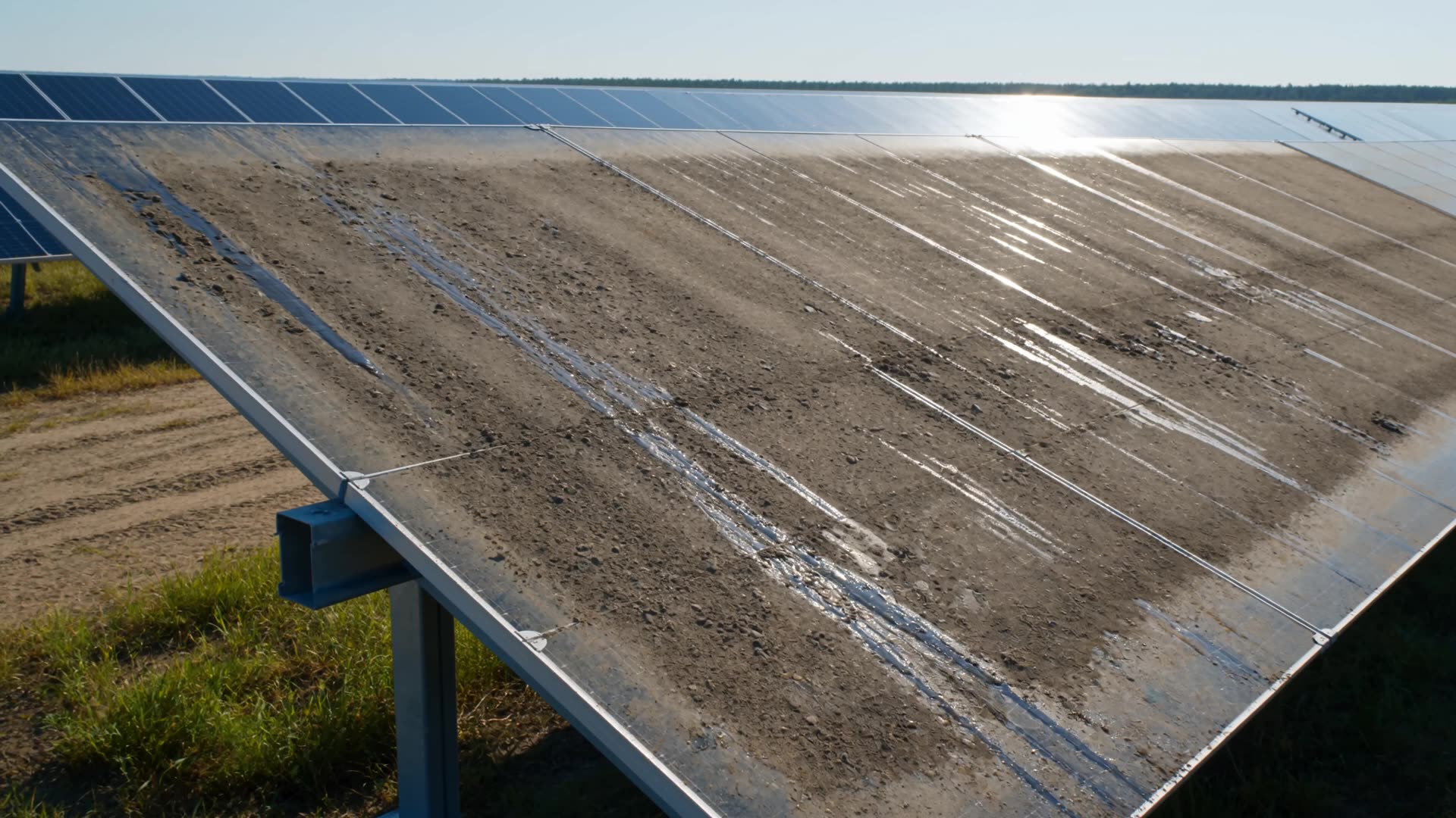 Utility-scale solar array coated in dried dust and soil, part-way through a professional pressure-cleaning pass